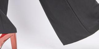 Close-up of a woman's black trousers and red high heels