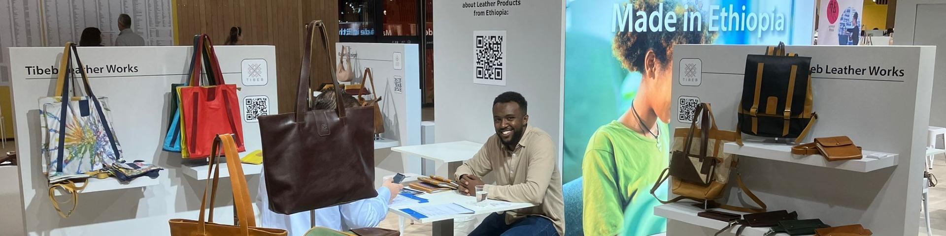 The Tibeb Leather Works stand at Who's Next 2024, with a company employee sitting surrounded by leather products