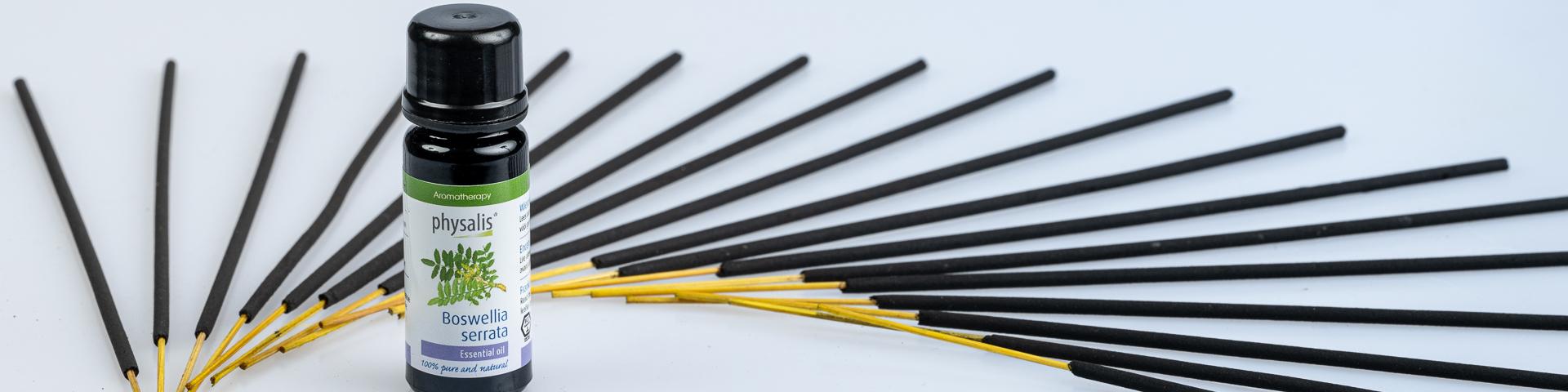 A bottle of Boswellia Serrata essential oil, with frankincense sticks in the background