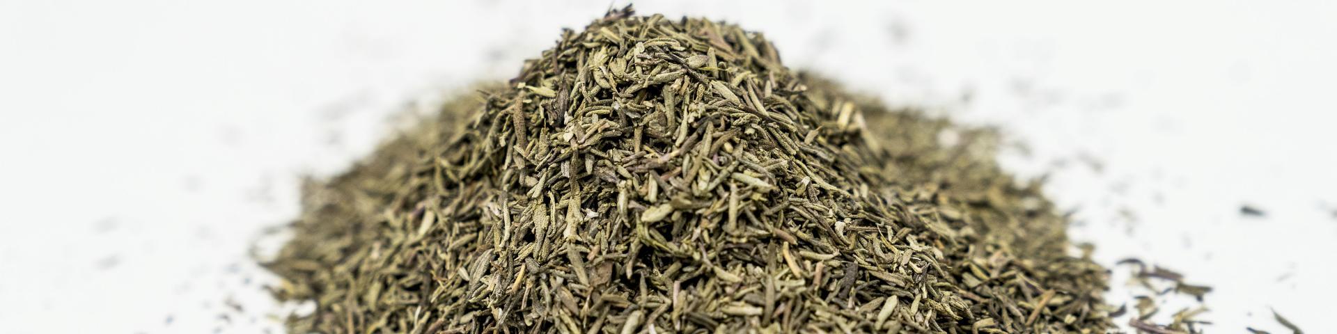 A heap of dried thyme against a white background
