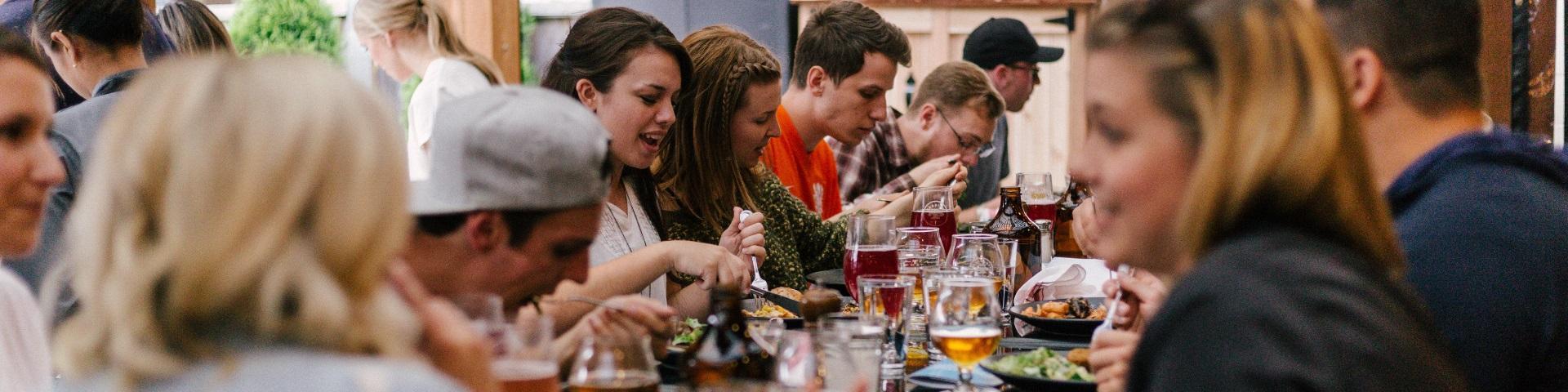 A large group of people eating and drinking together at a table