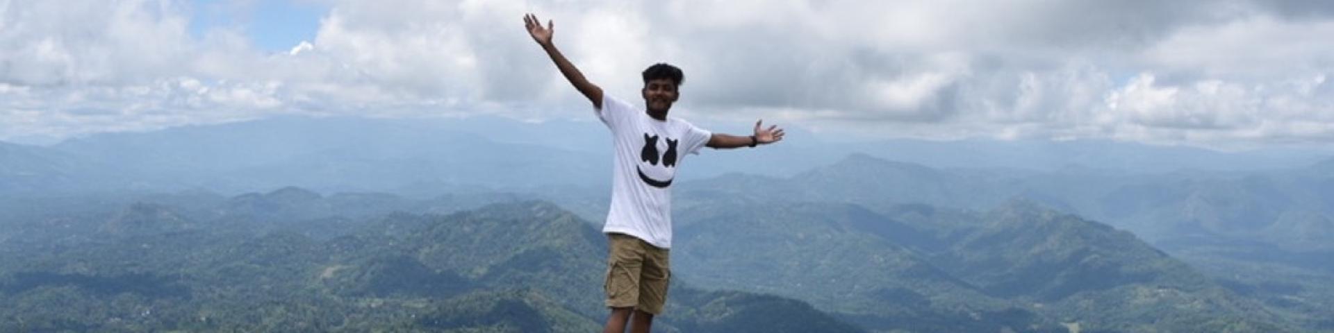 Person standing on rock with arms spread out