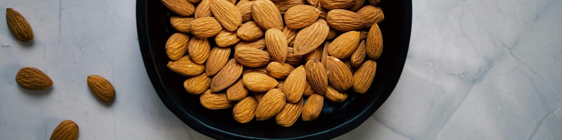 Almonds in a black bowl sat on top of a counter top