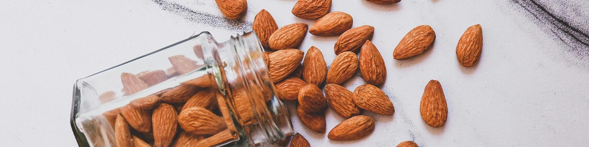 Almonds spilling out of a glass jar