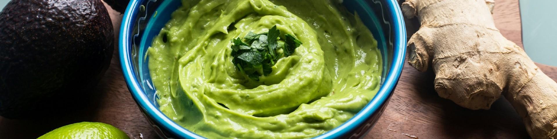 Avocado pulp in blue ceramic bowl, topped with coriander