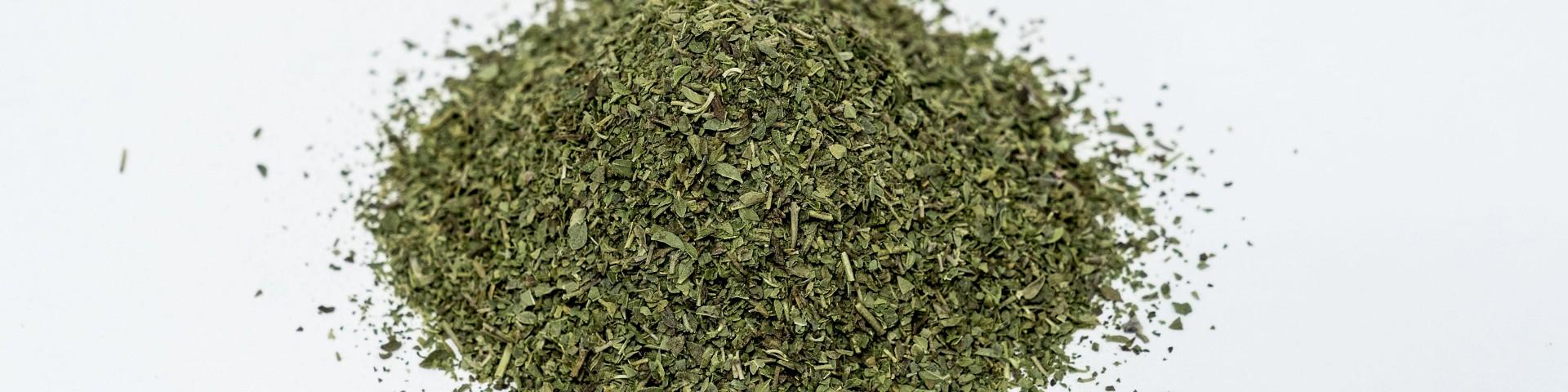 pile of dried oregano on a white surface