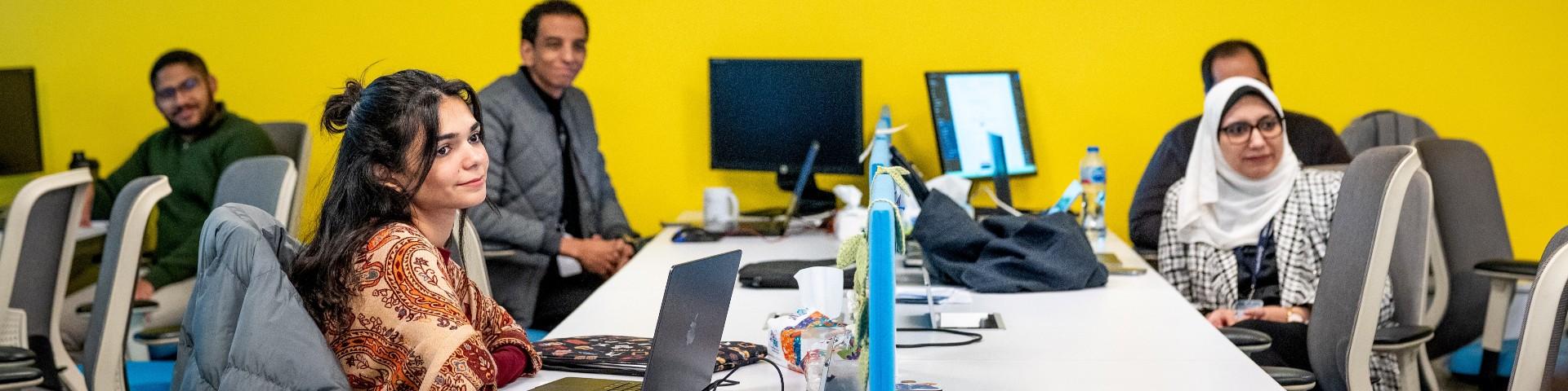 people behind their desks smiling and looking at a point off-camera