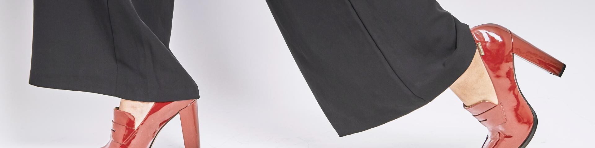 Close-up of a woman's black trousers and red high heels