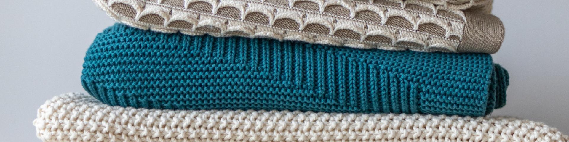 Close-up of three coloured blankets stacked on top of each other