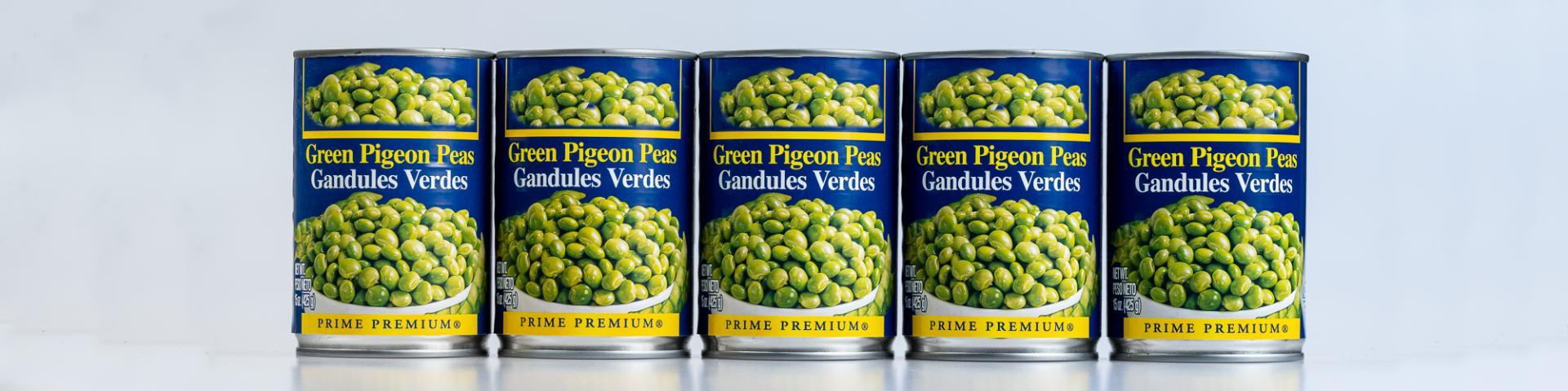 Four tins of green pigeon peas standing beside each other