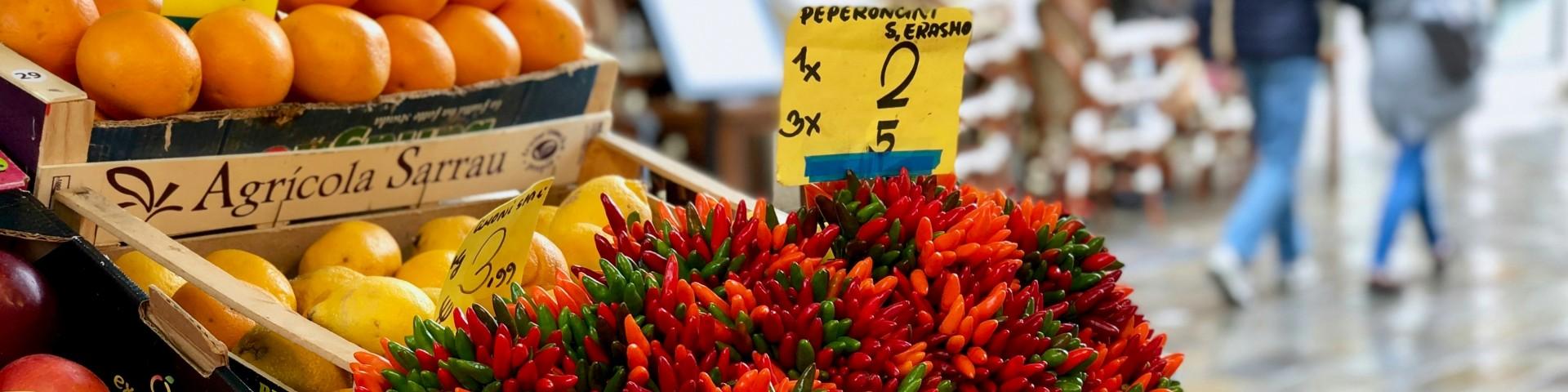 Market stall with chili peppers shown besides fruit