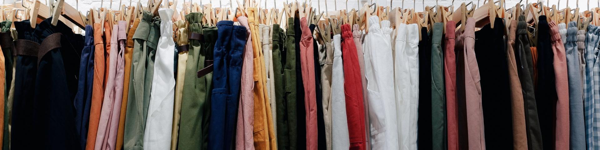 Pants and trousers of various colours and patterns hanging on a clothing rack