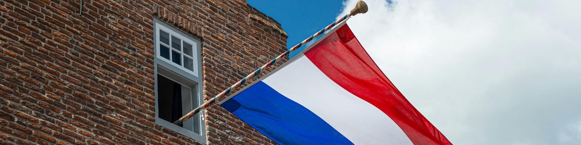 Dutch flag on a pole hanging out of a window