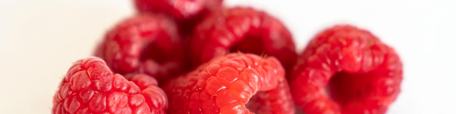 Six fresh raspberries against a white background