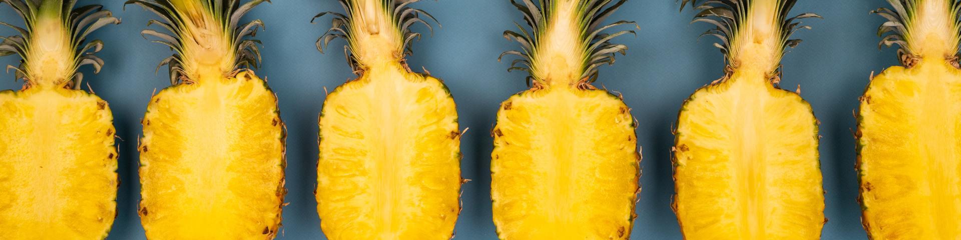 Six halved fresh pineapples placed in a row