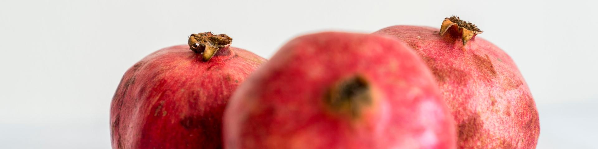 Three pomegranates against a white background