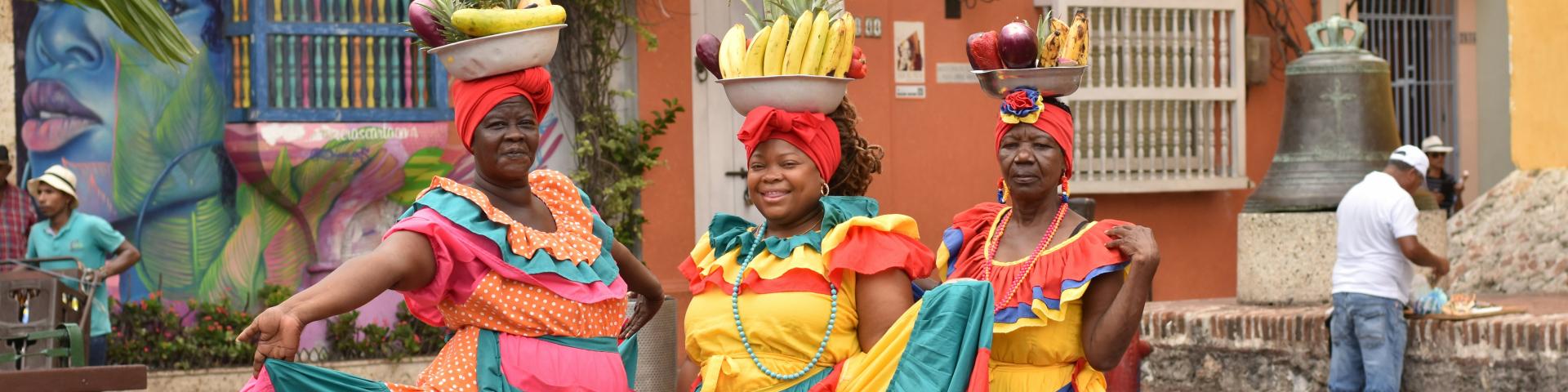 Three women in colourful dresses on a public square