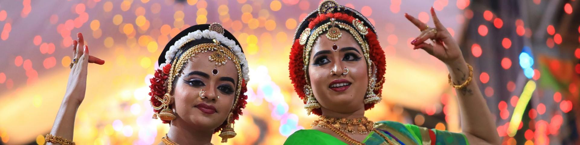 Two women dressed in traditional Indian garb, dancing
