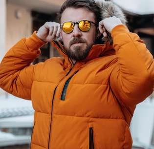 Man wearing orange puffer coat adjusting his sunglasses