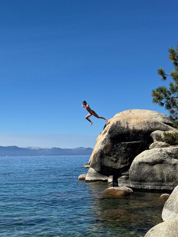 Person jumping of a rocky surface into the ocean