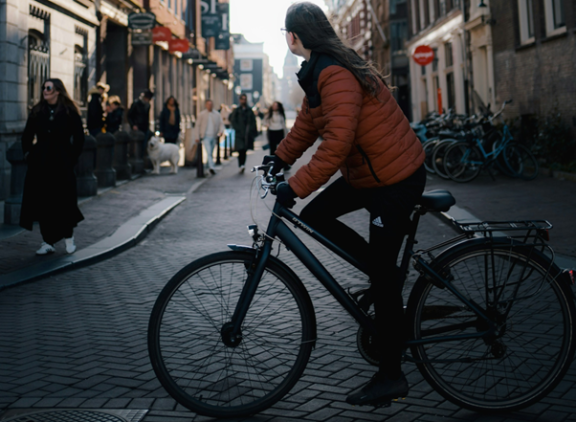 Woman cycling across a shopping street in the Netherlands