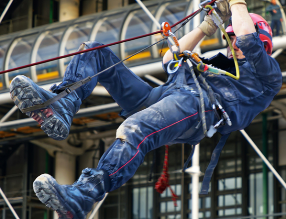 Worker wearing a harness climbing upward