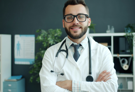 Doctor in uniform, looking at the camera while smiling and crossing their arms