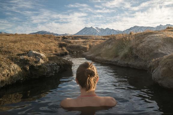 Woman shown from behind, bathing in a natural hot spring