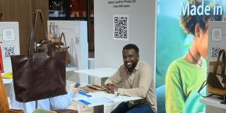The Tibeb Leather Works stand at Who's Next 2024, with a company employee sitting surrounded by leather products