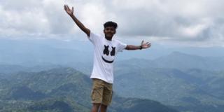 Person standing on rock with arms spread out