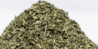 Pile of dried oregano against a white background