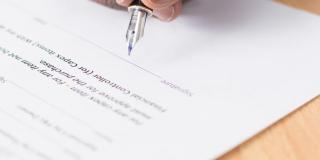 Close-up of a hand and pen signing a document