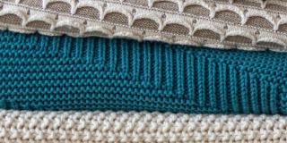 Close-up of three coloured blankets stacked on top of each other