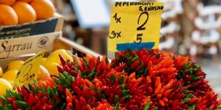 Market stall with chili peppers shown besides fruit