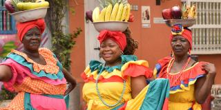 Three women in colourful dresses on a public square