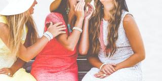 Three women wearing dresses talking with one another