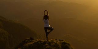 Person doing a yoga pose on top of a mountain