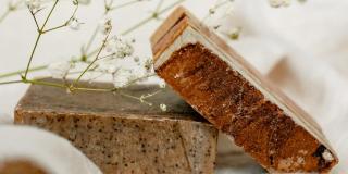 Two bars of soap with a plant placed on them, lying on a piece of white textile