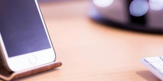 White phone on wooden stand next to white keyboard